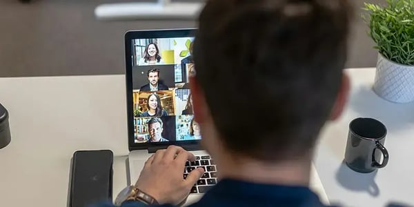 Person vor einem Laptop mit Onlinemeeting gibt Copilot Weiterbildung