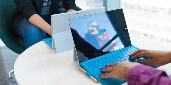 Person vor Microsoft Surface mit Copilot Logo auf dem Display