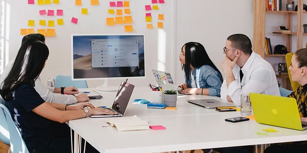 Microsoft Copilot Grundlagenschulung in einem hellen Meetingraum mit 5 Personen, die zu einem Bildschirm schauen